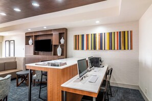A modern office space with a long desk, multiple monitors, and a flat-screen TV.