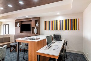 Un espacio de oficina moderno con un escritorio grande, múltiples monitores y un televisor de pantalla plana.