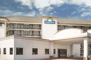 A Days Inn hotel with a modern design, featuring a prominent sign, multiple balconies, and a covered entrance area.