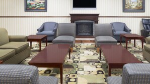 A room with a fireplace, two sofas, and four armchairs arranged around a coffee table. - Days Inn by Wyndham Columbus-North Fort Moore (Columbus)