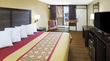 A hotel room with a large bed, a TV, a chair, and a desk.