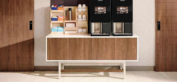 A modern kitchen with wooden cabinets, a white countertop, and two coffee machines.