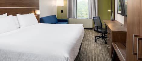 Habitación de hotel con una cama grande, un escritorio, una silla y un televisor.