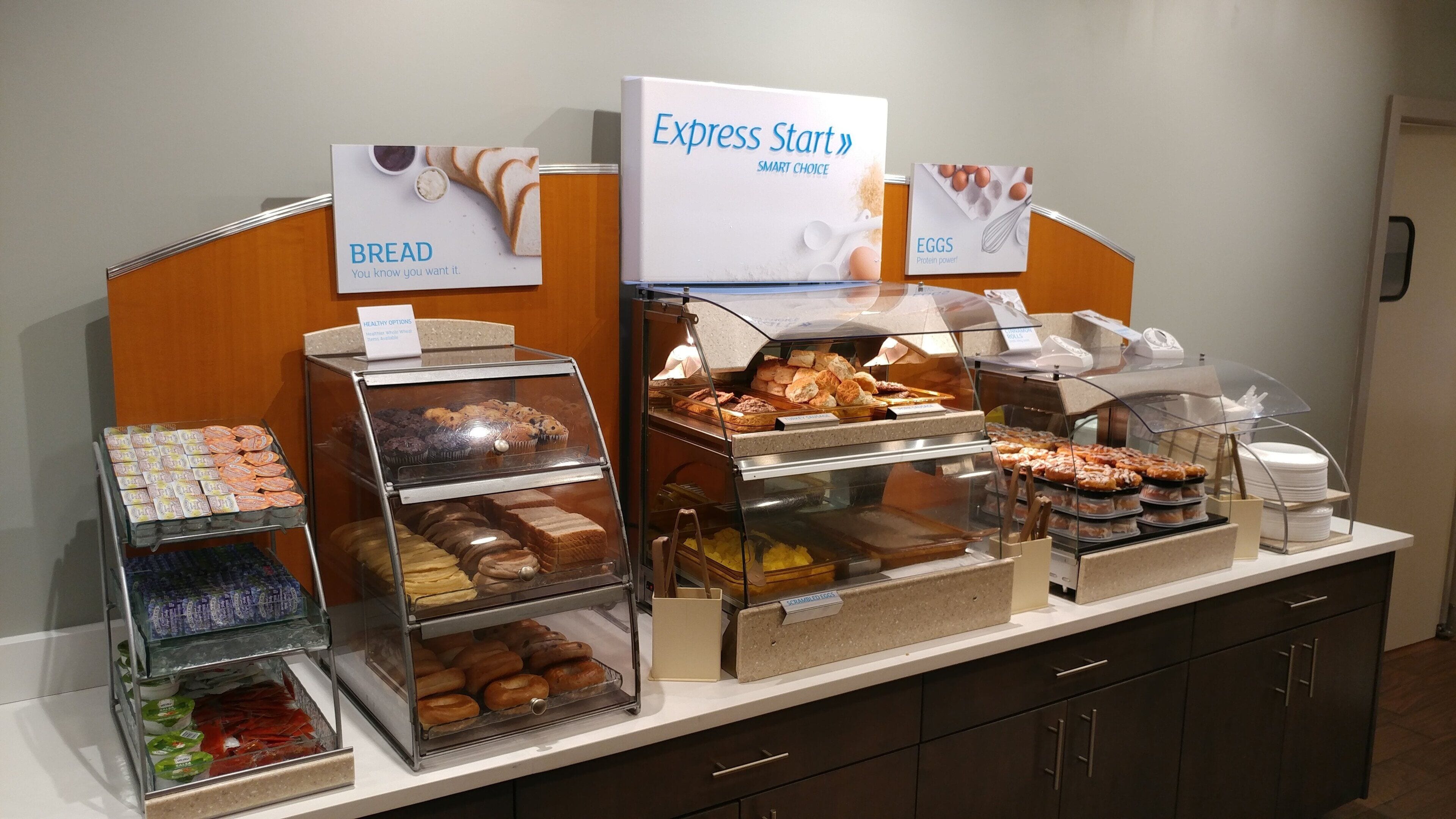 A buffet with labeled sections for bread, eggs, and a variety of pastries.