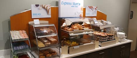 A buffet with labeled sections for bread, eggs, and a variety of pastries.
