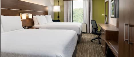 A hotel room with two beds, a desk, a chair, a TV, and a window with curtains.