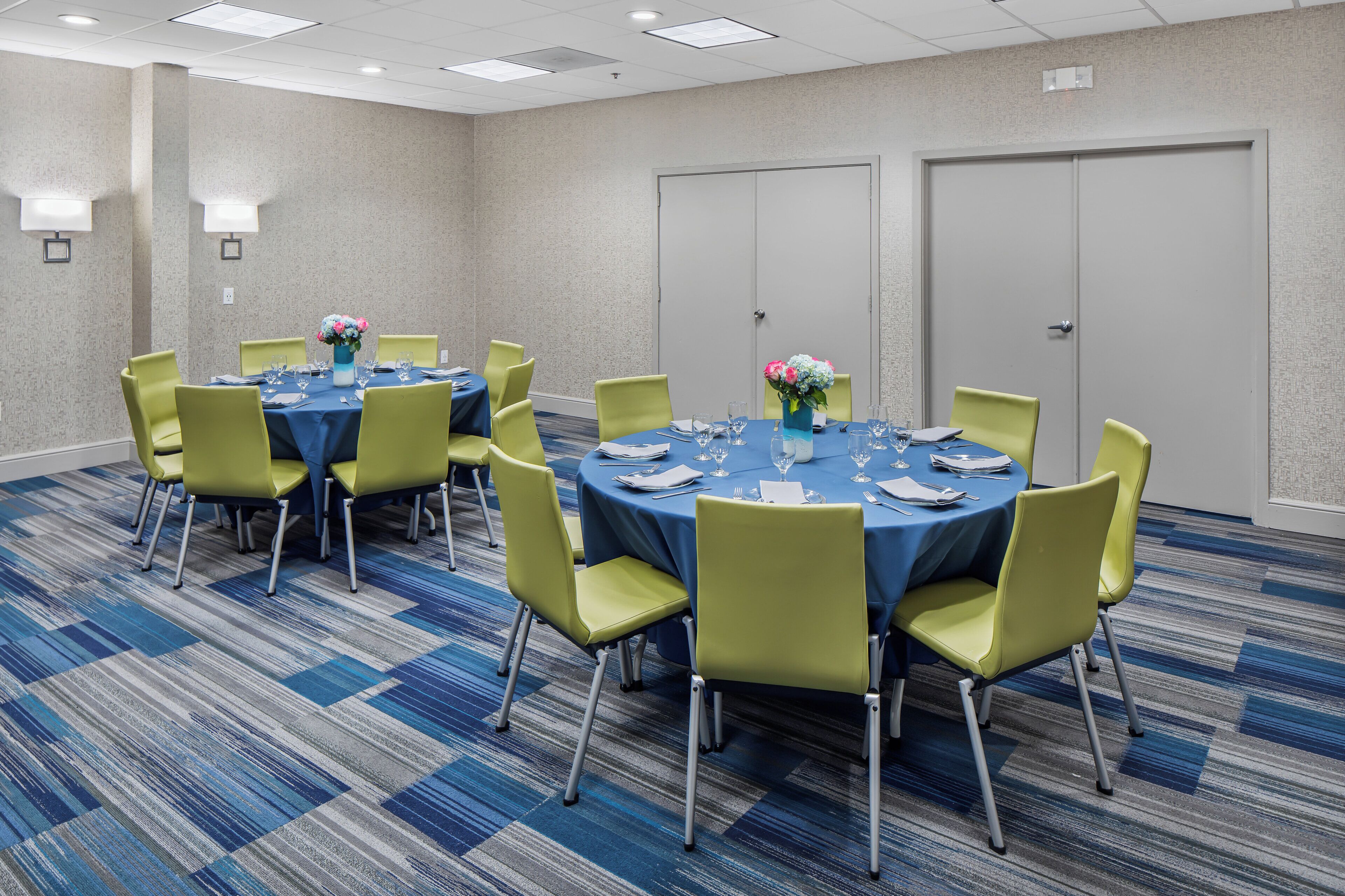 A conference room with round tables, chairs, and floral centerpieces.