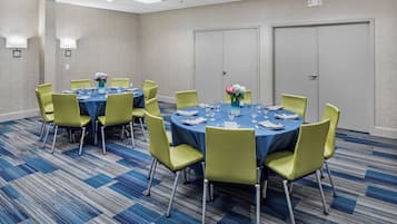 A conference room with round tables, chairs, and floral centerpieces.