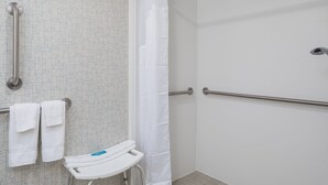 A bathroom with a shower, grab bars, a wheelchair-accessible bench, and a towel rack. - Holiday Inn Express Atlanta Airport - College Park by IHG (College Park)