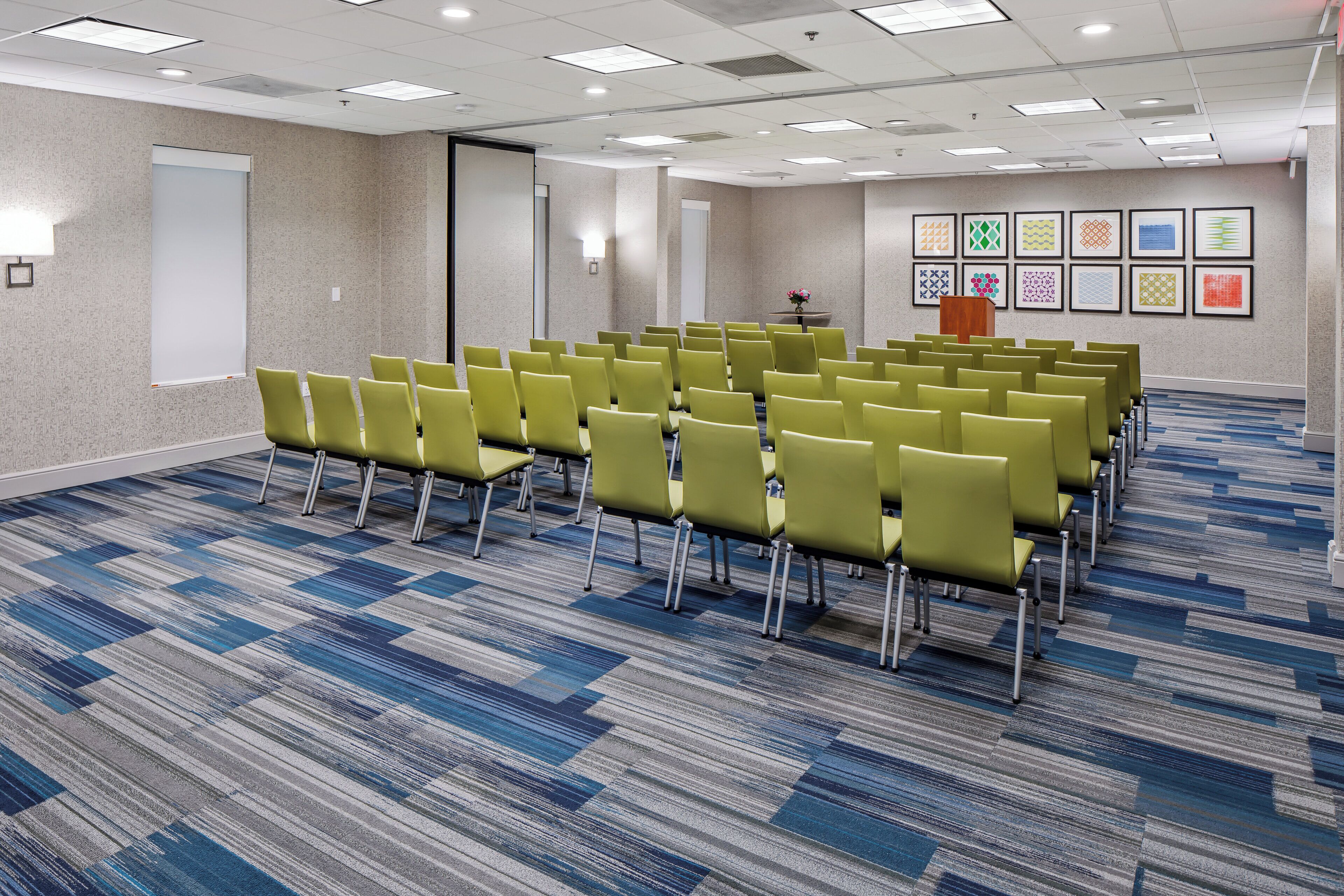 A conference room with rows of chairs, a whiteboard, and a podium.