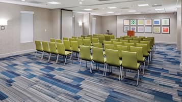 A conference room with rows of chairs, a whiteboard, and a podium.
