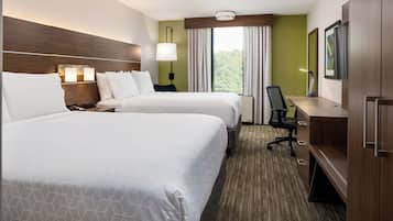 A hotel room with two beds, a desk, a chair, a TV, and a window with curtains.