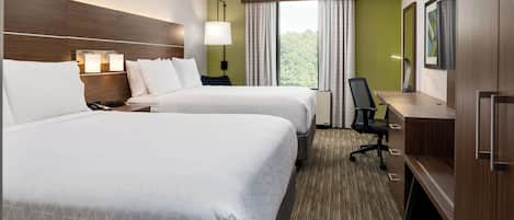 A hotel room with two beds, a desk, a chair, a TV, and a window with curtains.