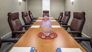 A conference room with a long wooden table, brown leather chairs, and a chandelier. - Holiday Inn Express Atlanta Airport - College Park by IHG (College Park)