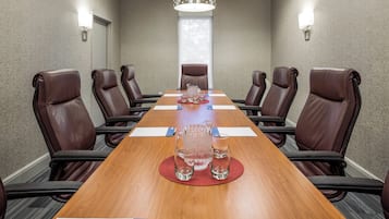 A conference room with a long wooden table, brown leather chairs, and a chandelier.