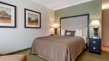 Habitación de hotel con una cama grande, dos mesitas de noche con lámparas, un cabecero y dos cuadros enmarcados en la pared.