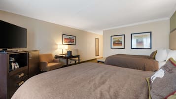 Habitación de hotel con una cama grande, un escritorio con lámpara, televisión y dos cuadros en la pared.