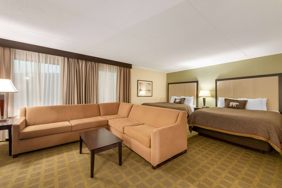 A hotel room with a sofa, a bed, a nightstand, and a lamp.