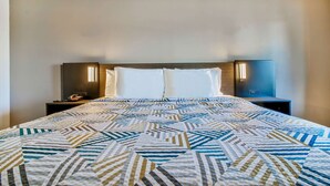 Una habitación de hotel con una cama grande, dos mesitas de noche y una lámpara fijada a la pared.