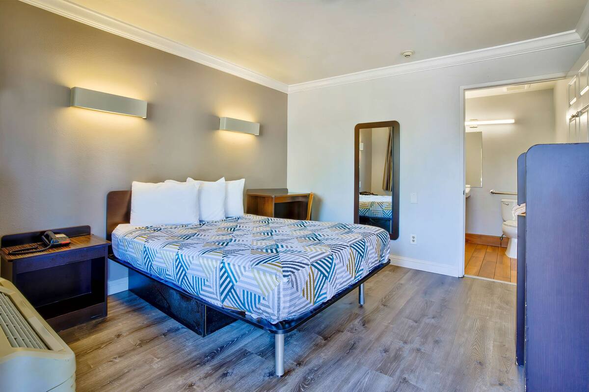 Quarto com cama, mesa de cabeceira e espelho.