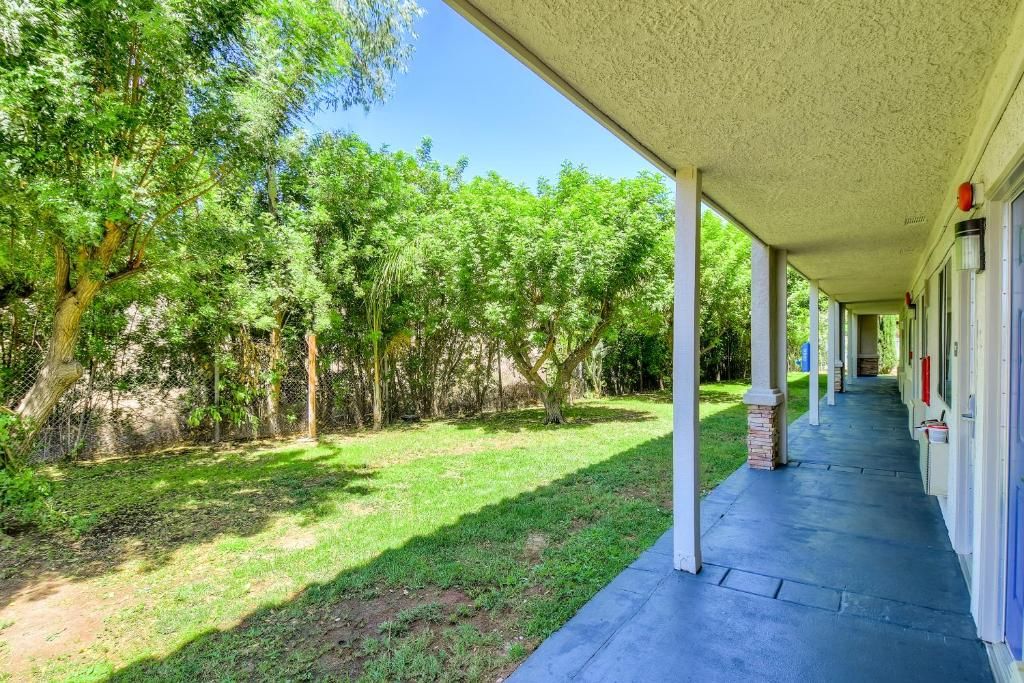 Un espacio al aire libre cubierto con un camino que lleva a un edificio, rodeado de árboles.