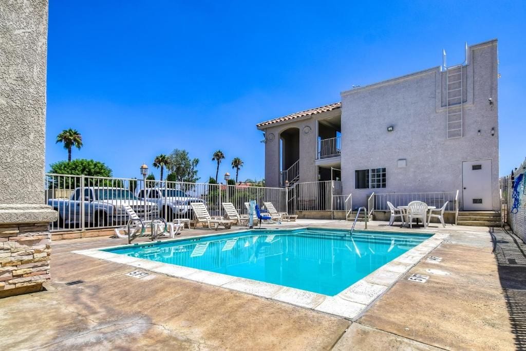A swimming pool with lounge chairs and a building with a balcony.
