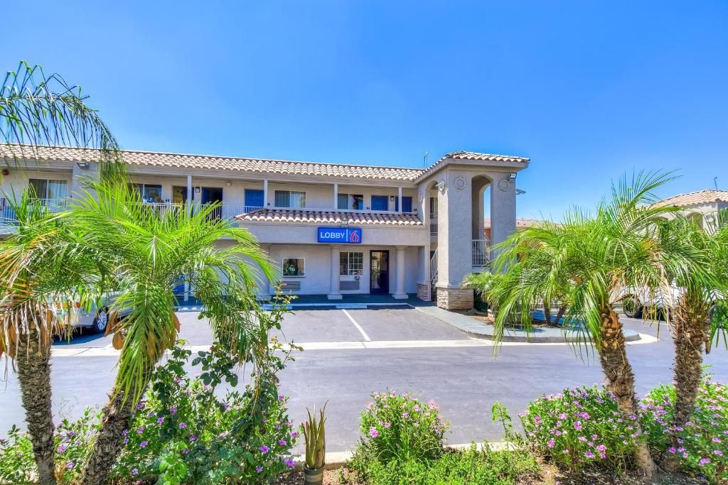 A hotel with a lobby entrance, palm trees, and a clear blue sky.