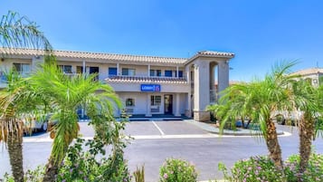 A hotel with a lobby entrance, palm trees, and a clear blue sky.