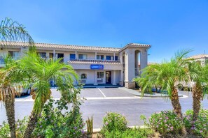 A hotel with a lobby entrance, palm trees, and a clear blue sky. - Motel 6 Menifee, CA (Menifee)