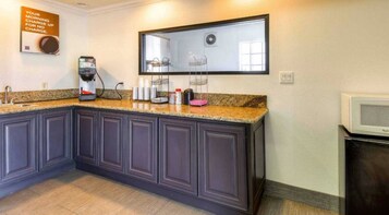 Una cocina con armarios oscuros, encimera de granito, cafetera y microondas.