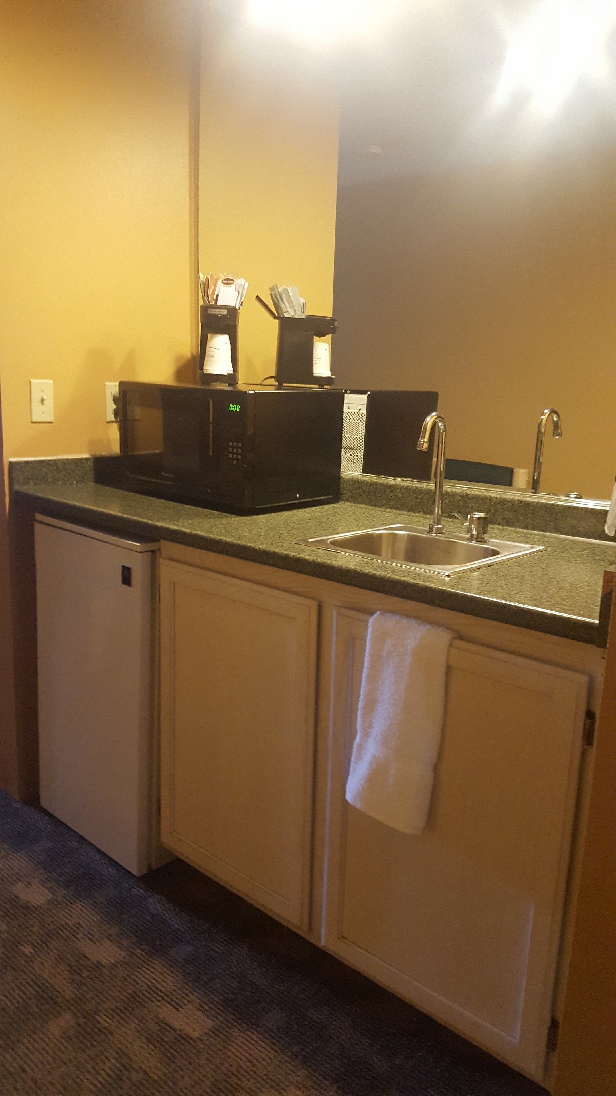 A compact kitchen with a sink, a coffee machine, and a microwave.
