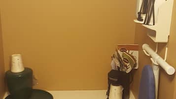 Una kitchenette pequeña con cafetera, hervidor de agua y microondas. Hay una toalla colgada en la pared y una repisa con utensilios.