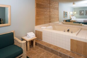A bathroom with a bathtub, a wooden bench, a small stool, and a mirror.