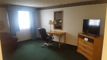 Een hotelkamer met een bureau, stoel, televisie en een dressoir.