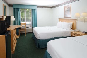 Two single beds with white linens, a desk with TV and lamp, and a chair.