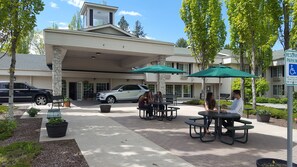 Relax in our outdoor patio area, surrounded by lush greenery and trees, with comfortable seating and convenient parking available.