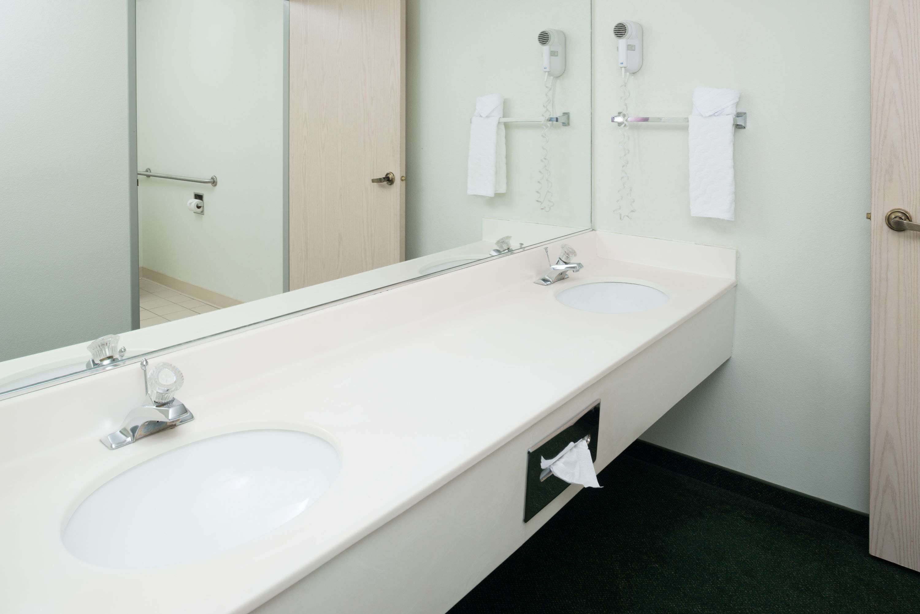A bathroom with two sinks, a mirror, a towel rack, and a hairdryer.