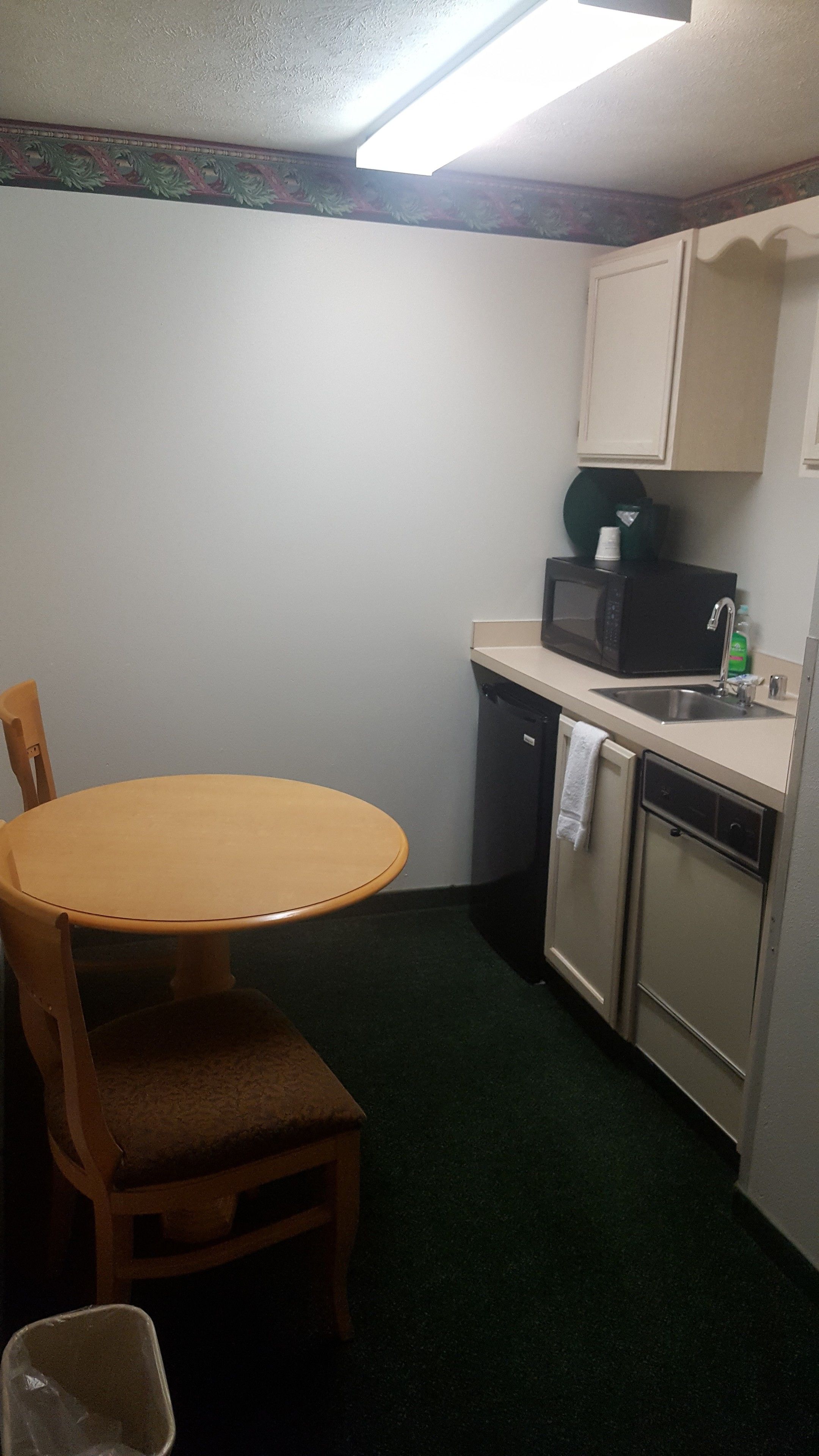 A compact kitchen with a round table and chairs, a microwave, a sink, and a dishwasher.
