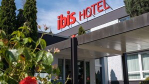 Exterior del hotel ibis con un diseño moderno, que destaca un llamativo letrero rojo y una zona de acceso cubierta.