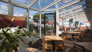 Un restaurante con paredes de vidrio, mesas y sillas de madera.