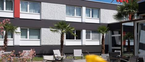 Un hotel de diseño moderno, con techo plano, varias ventanas y un llamativo letrero rojo.