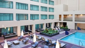A hotel lobby with a pool, seating areas, and a large windowed atrium.