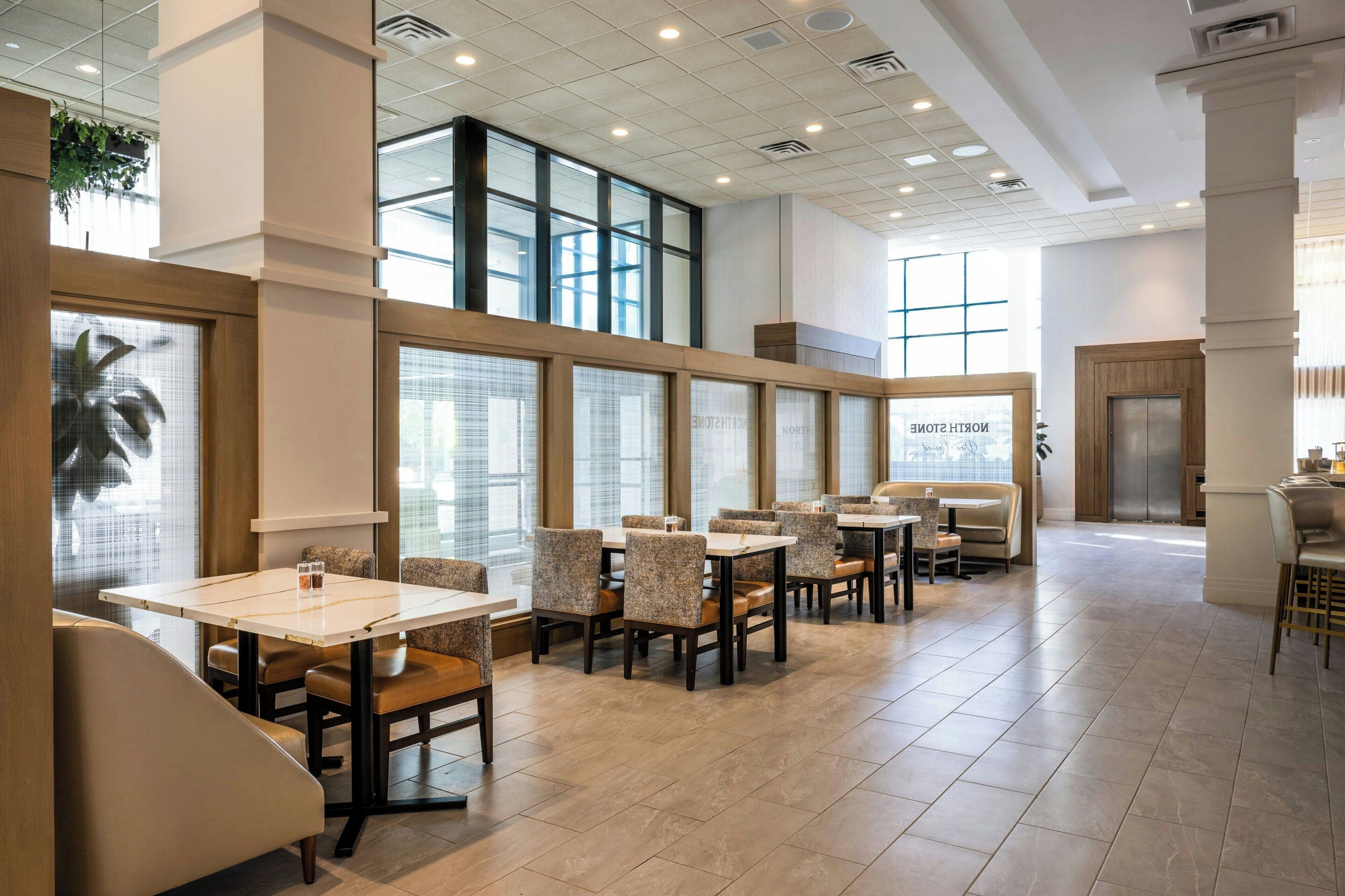 A modern restaurant with high ceilings, large windows, and a clean, organized layout.
