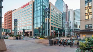A Marriott hotel with a modern glass facade, a prominent sign, and a landscaped courtyard with bicycles.