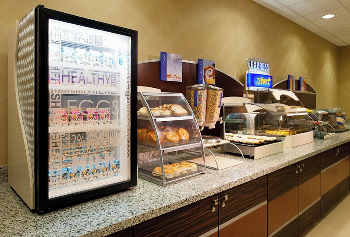 A buffet setup with various food items and a refrigerated display case.
