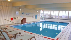 An indoor swimming pool with no diving signs, a lifeguard chair, and a pool ladder.