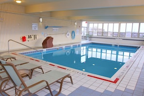 Una piscina interior sin señales de prohibición de clavados, una silla de salvavidas y una escalera de piscina.