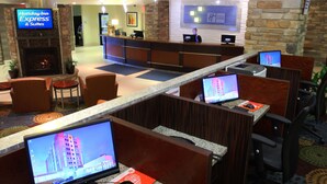 A hotel lobby with a reception desk, computer workstations, seating areas, and a fireplace.