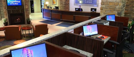 A hotel lobby with a reception desk, computer workstations, seating areas, and a fireplace.