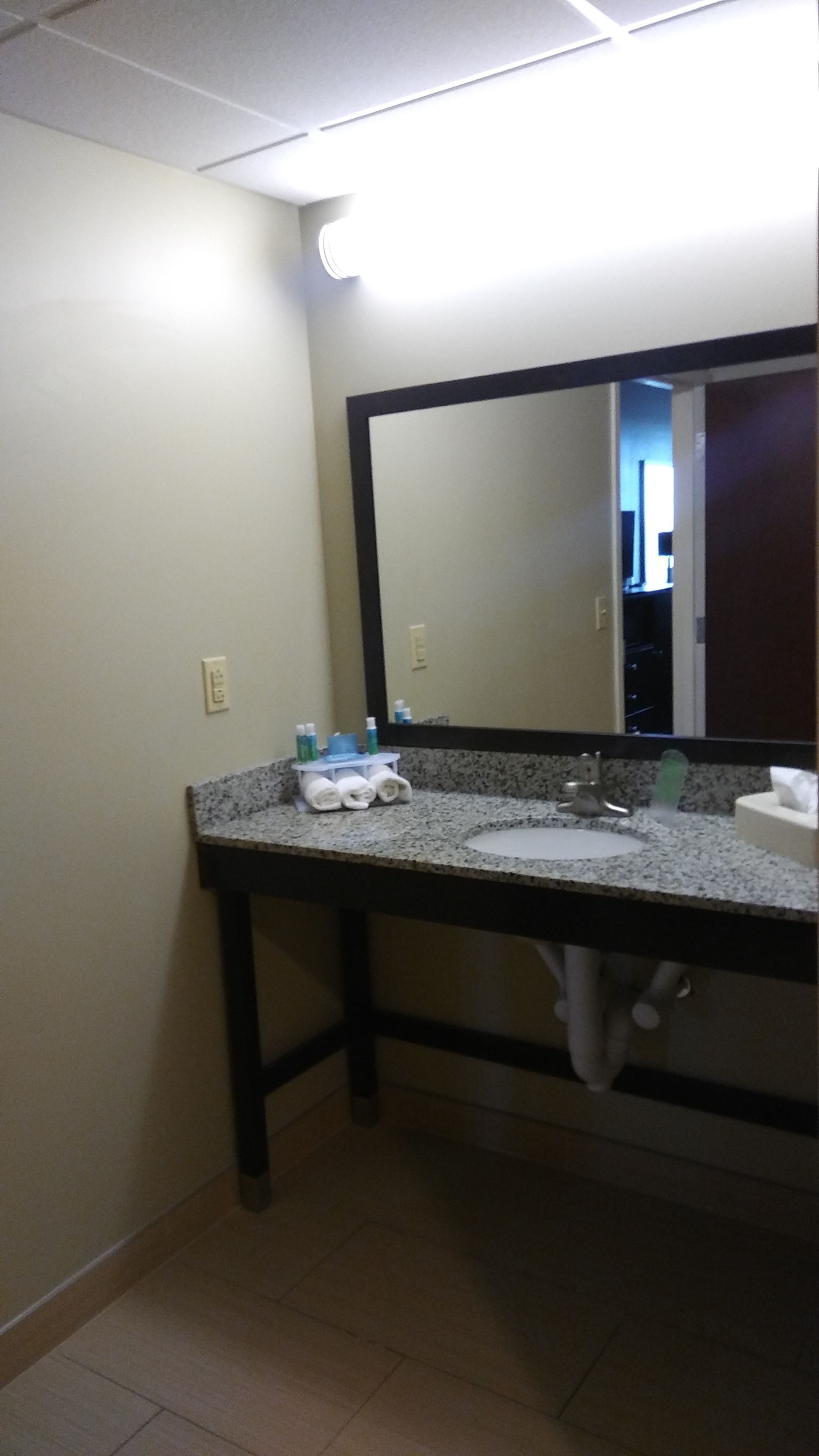 A bathroom with a granite countertop, a sink, a mirror, and a towel rack.